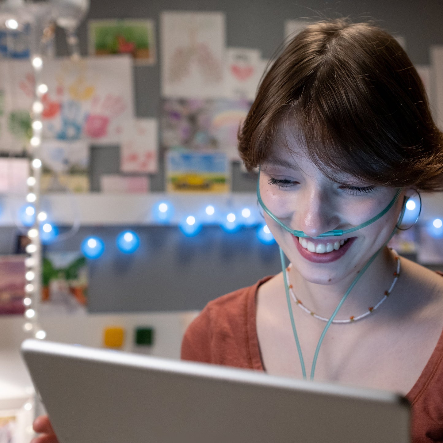 Female smiling working on laptop while wearing nasal cannula