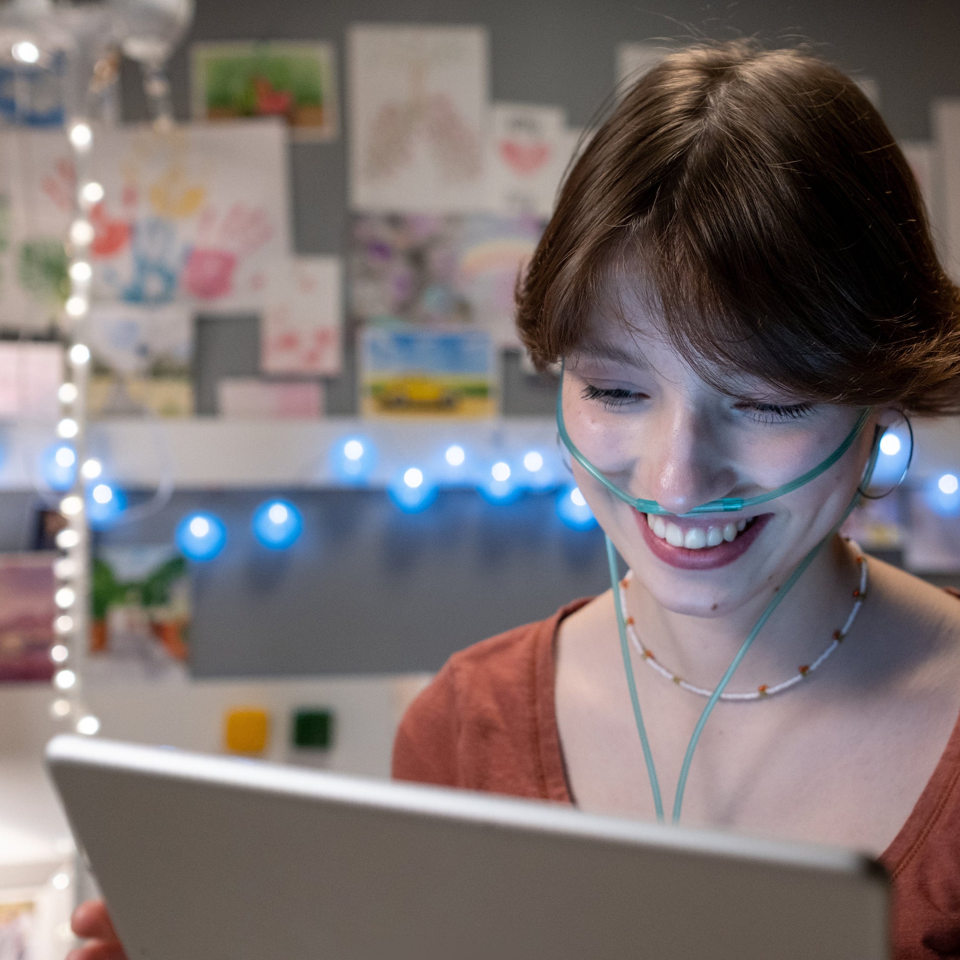 Female smiling working on laptop while wearing nasal cannula